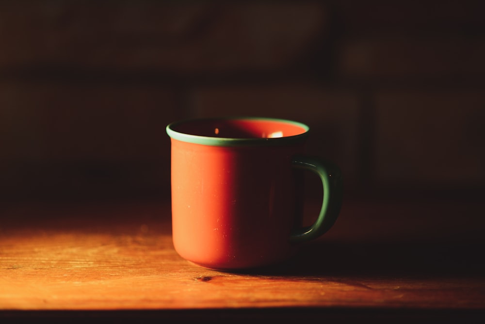 red ceramic mug on brown wooden table