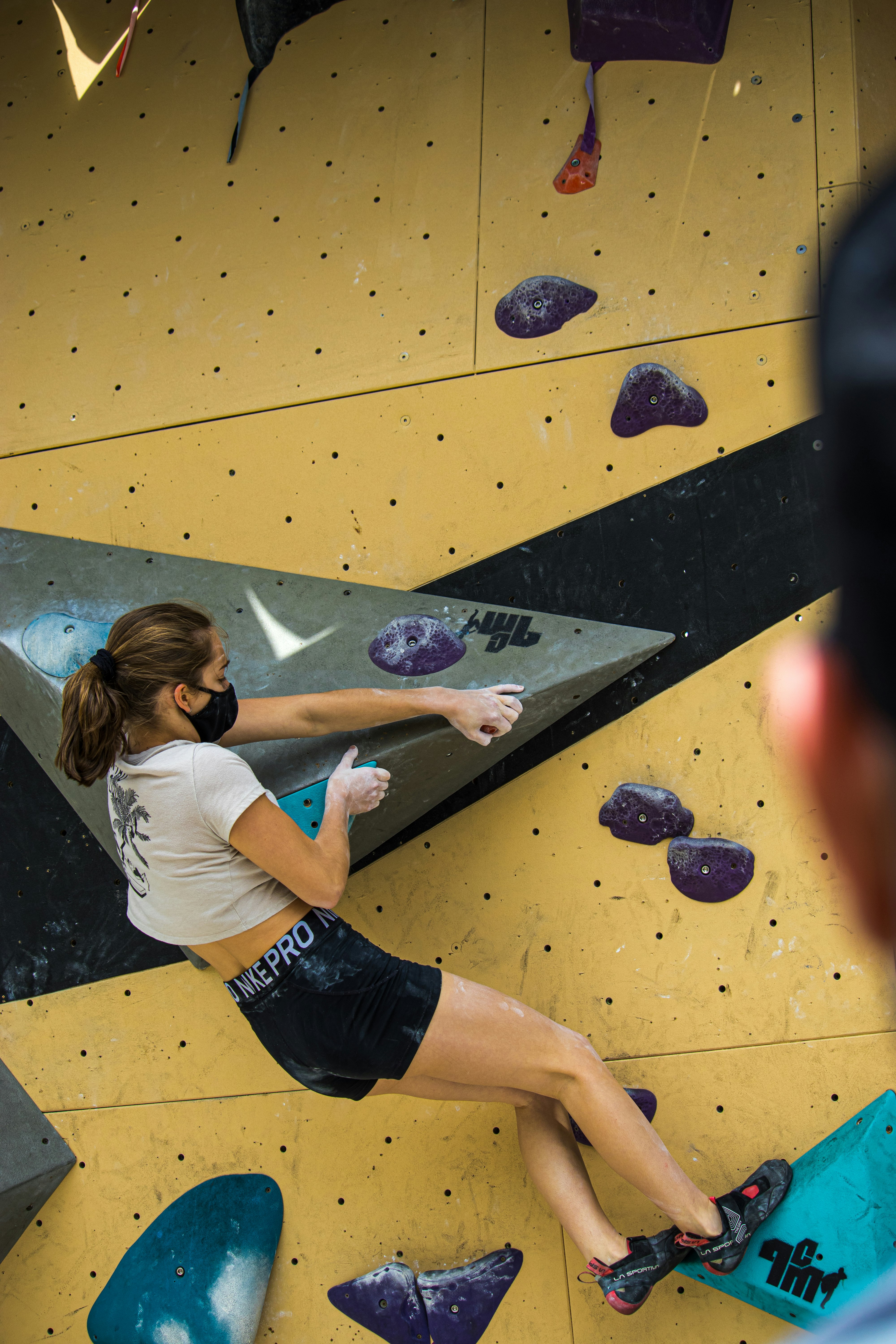 Girl climbing a V6 problem on an outside artificial bouldering wall.