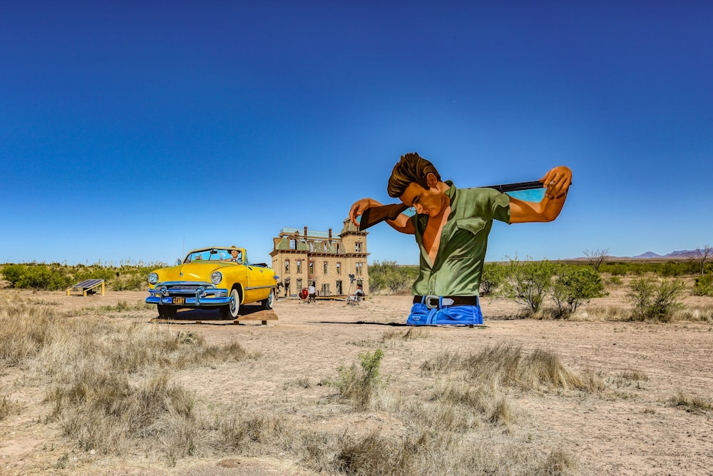 man in green t-shirt and blue denim jeans standing beside yellow car during daytime