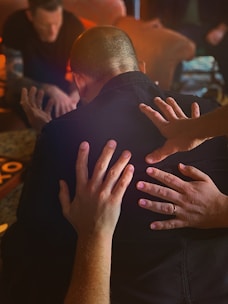 man in black shirt covering face with both hands