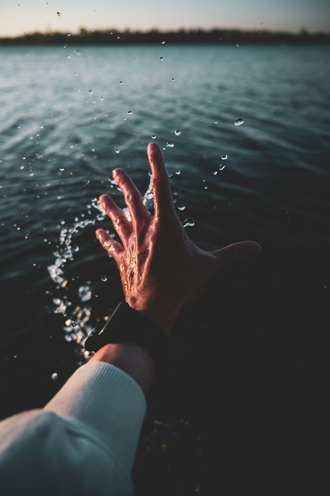 person in white long sleeve shirt with left hand on water