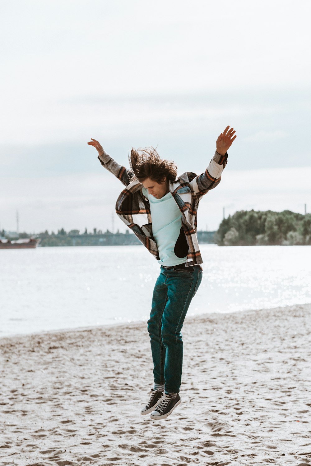 woman in white long sleeve shirt and green pants standing on beach during daytime