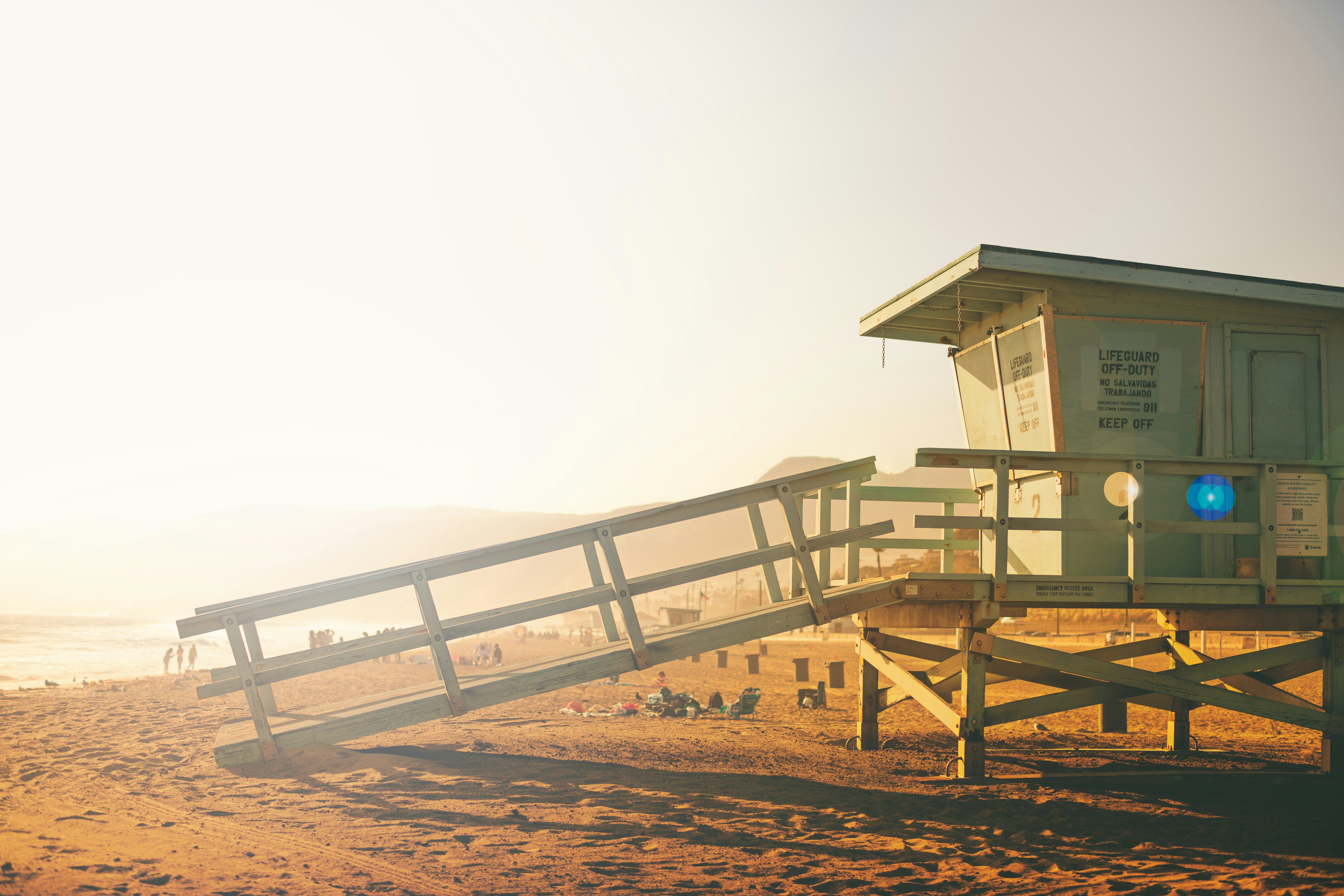 white wooden house on brown sand under white sky during daytime