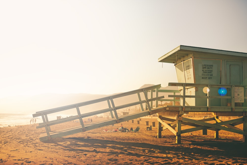 white wooden house on brown sand under white sky during daytime