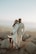 man in white suit standing beside woman in white dress on rock during daytime