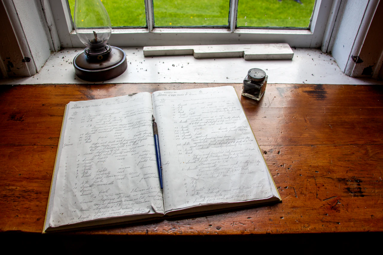 An open notebook and pen on a sunlit wooden desk