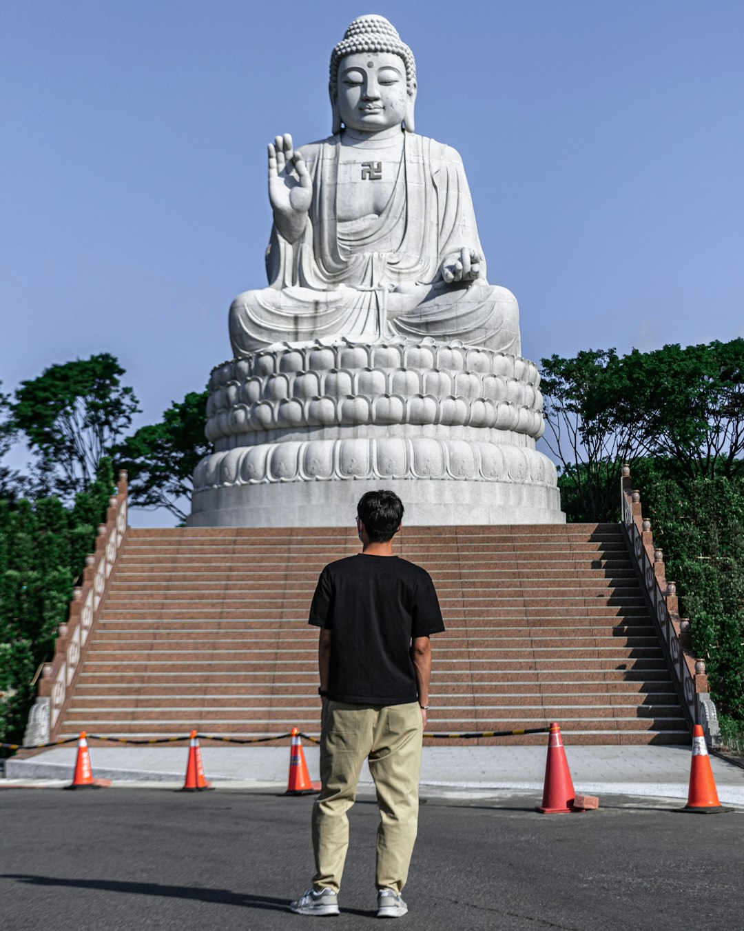 man in black shirt and brown pants standing in front of white statue