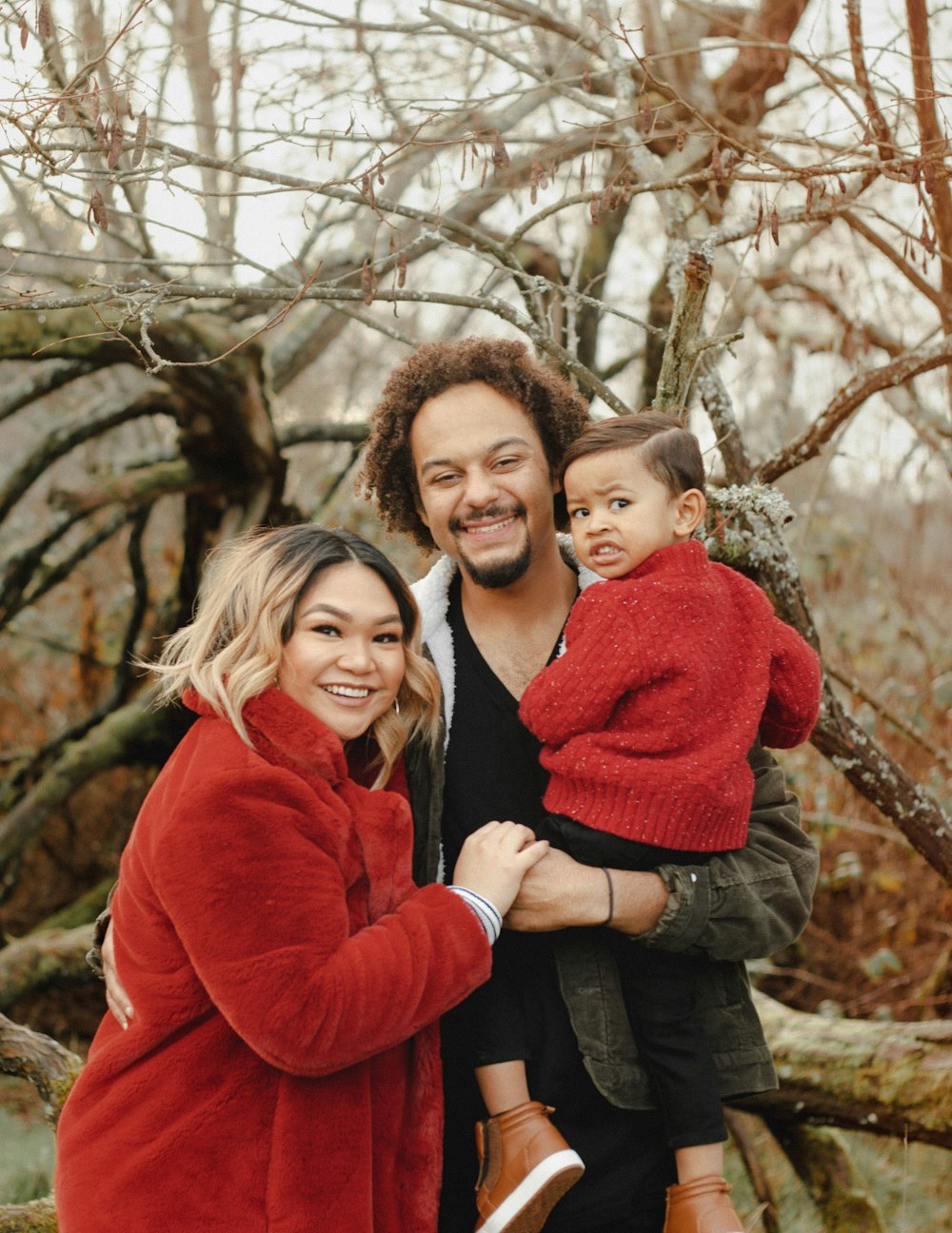 woman in red sweater carrying boy in black jacket