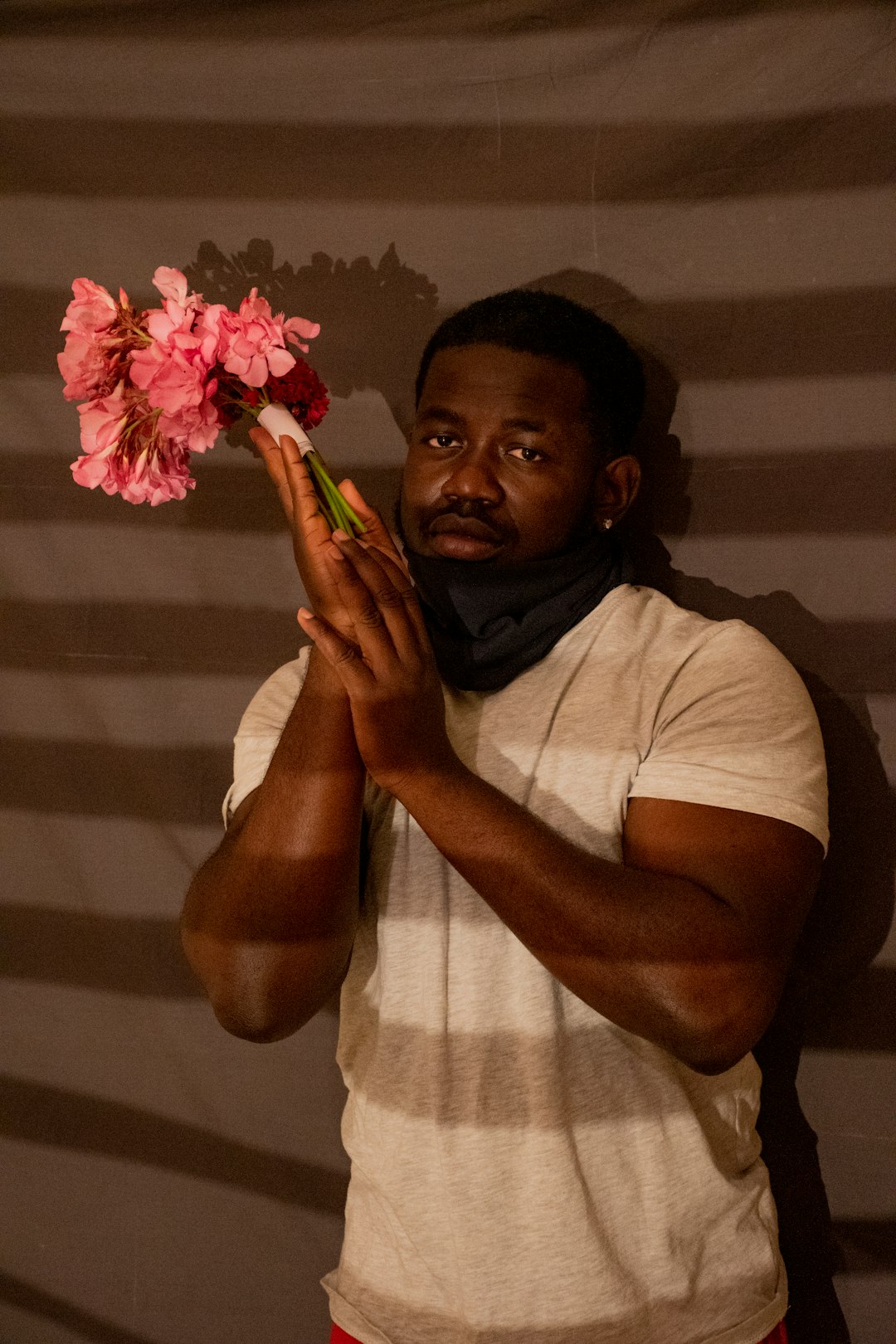 man in white crew neck t-shirt holding red flower