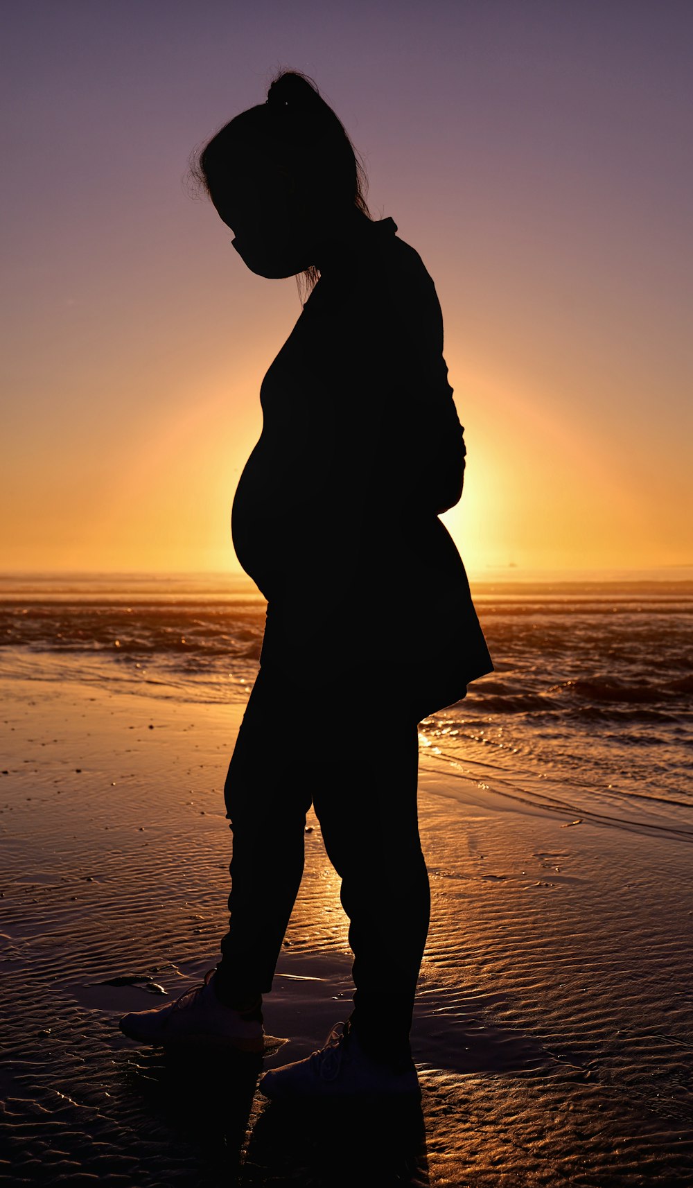 silhouette of woman standing on beach during sunset