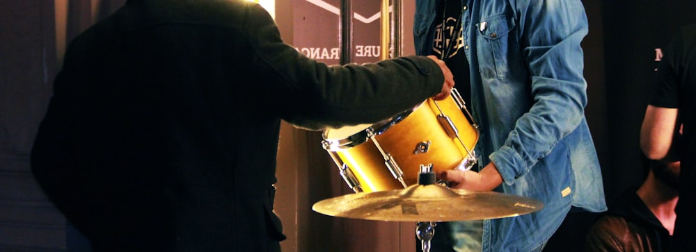 Persona in camicia nera a maniche lunghe che suona il tamburo marrone e bianco