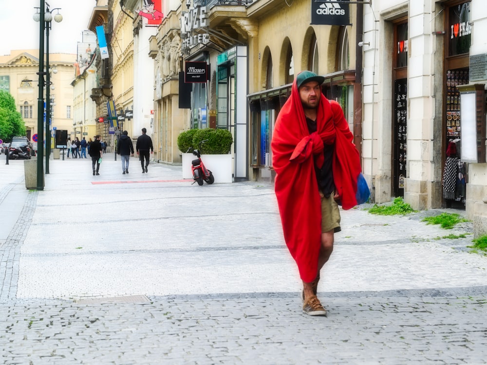 woman in red robe walking on sidewalk during daytime