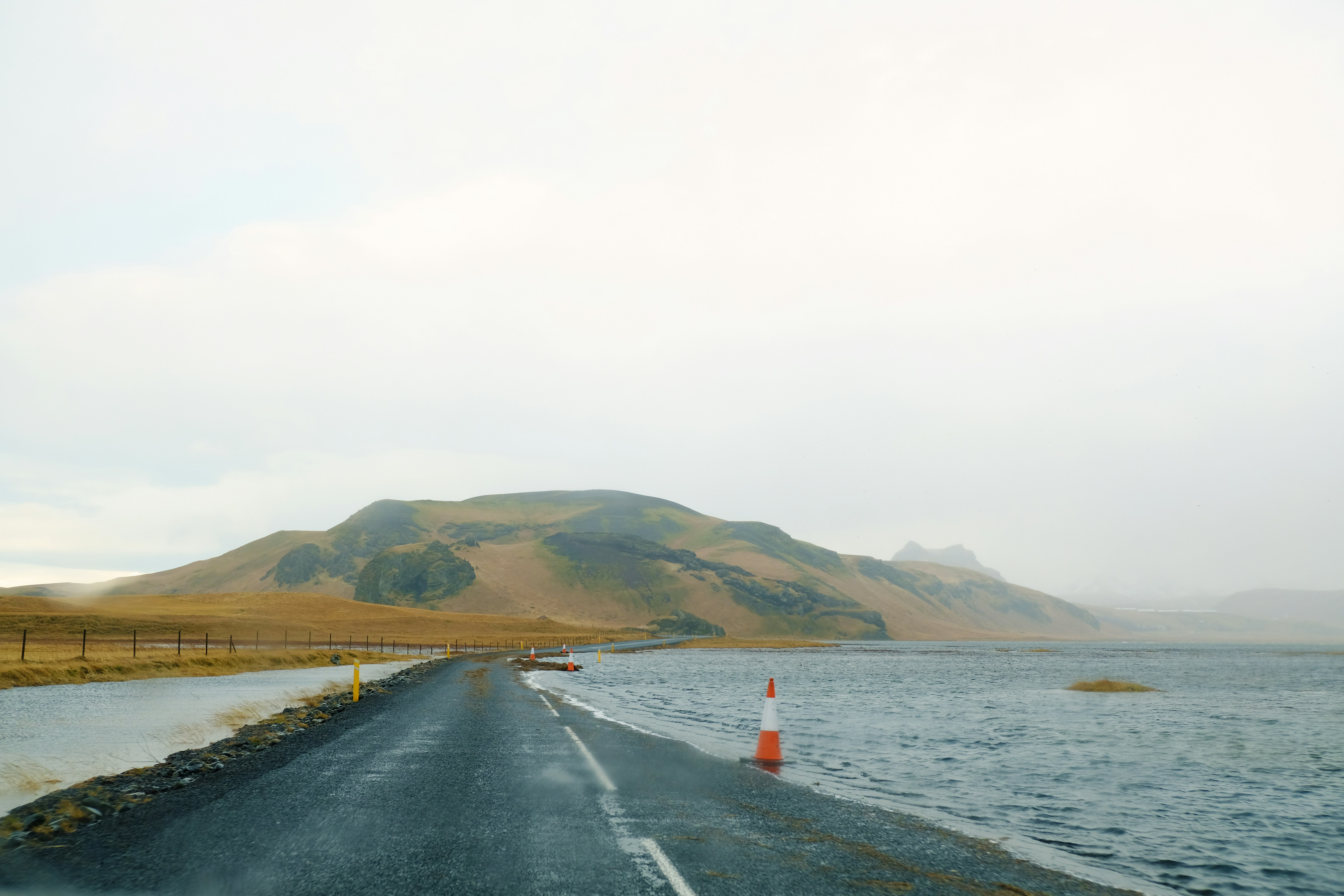 person in red shirt standing on black asphalt road during daytime