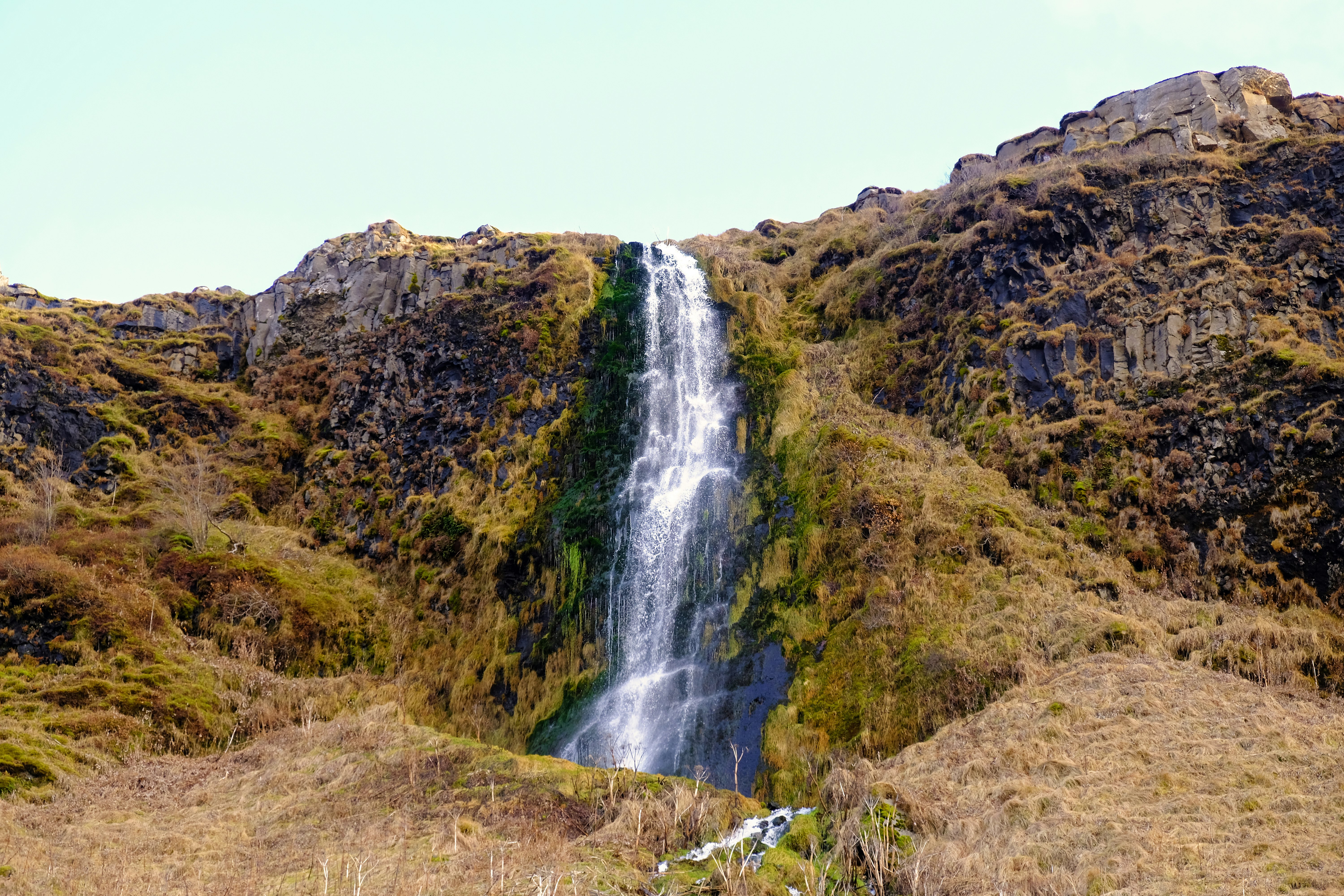 waterfalls in the middle of green and brown mountain