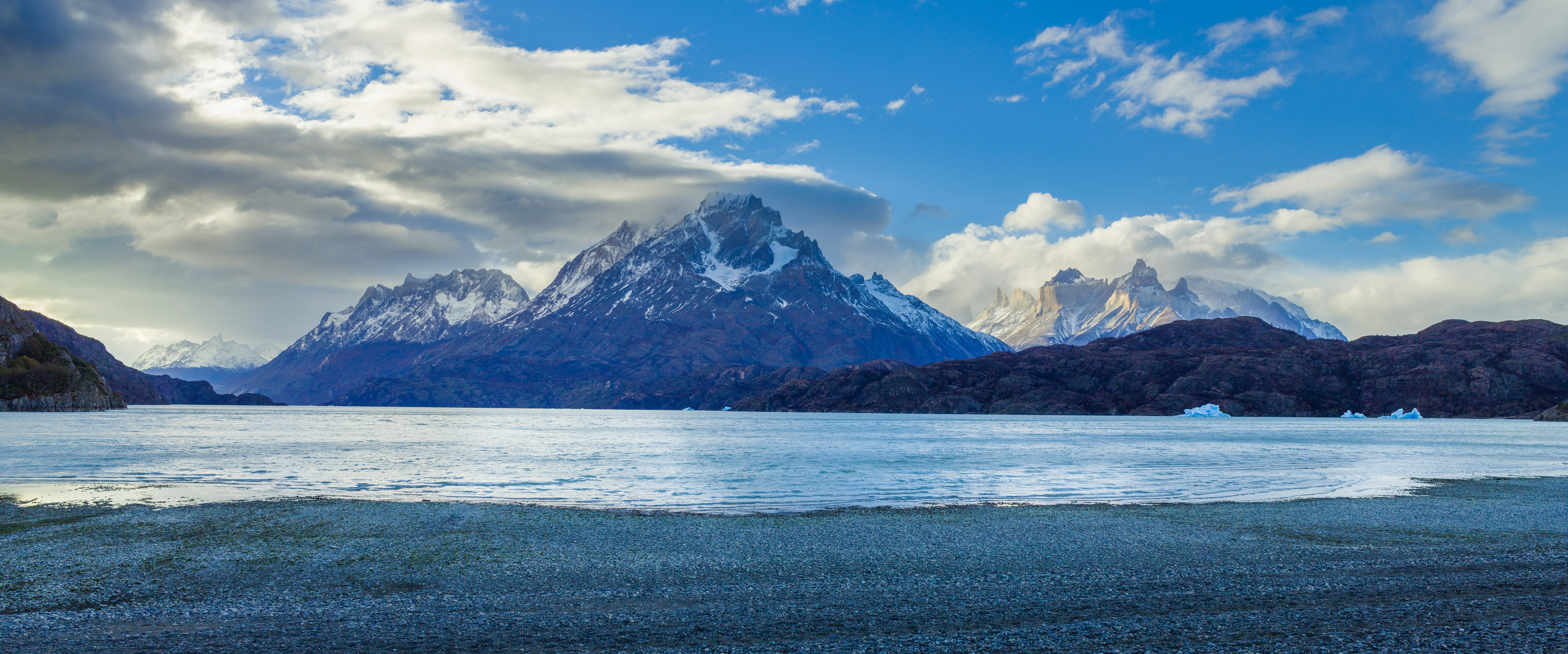 snow covered mountain near body of water during daytime