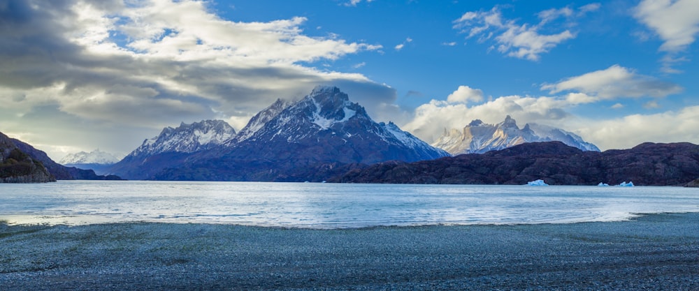 snow covered mountain near body of water during daytime