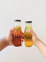 person holding orange juice in glass jar