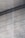 A textured concrete surface with fine grooves and scattered small holes. Diagonal shadows cast across the surface add depth and a sense of dimension.