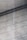 A textured concrete surface with fine grooves and scattered small holes. Diagonal shadows cast across the surface add depth and a sense of dimension.