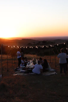 A peaceful retreat setting with a group gathered in prayer outdoors at sunset.