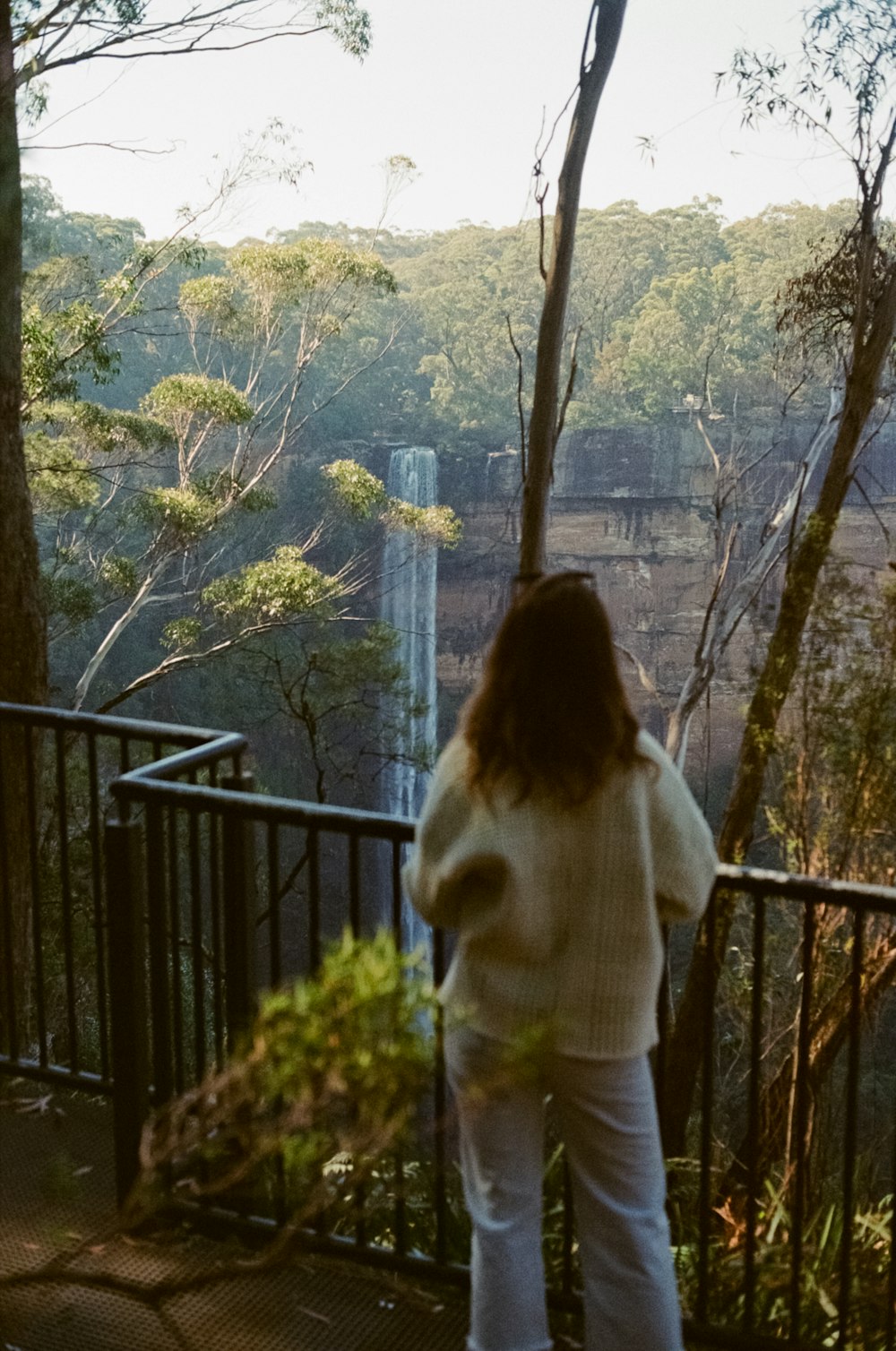 woman in white sweater standing on balcony during daytime