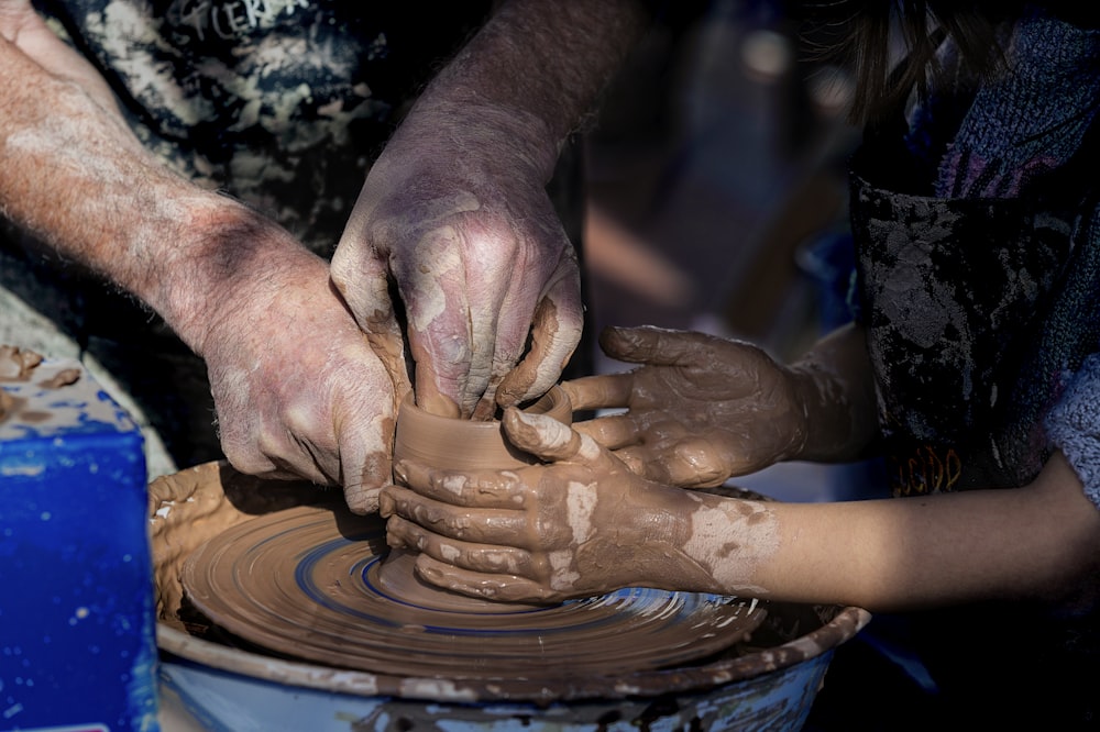 person making clay pot with clay
