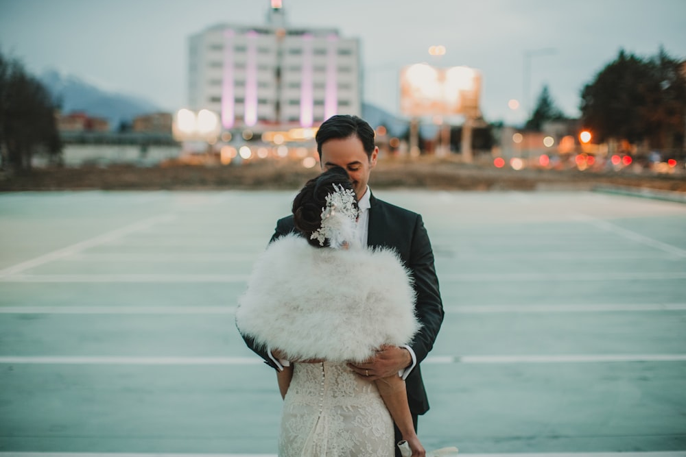 man in black suit kissing woman in white wedding dress on beach during daytime