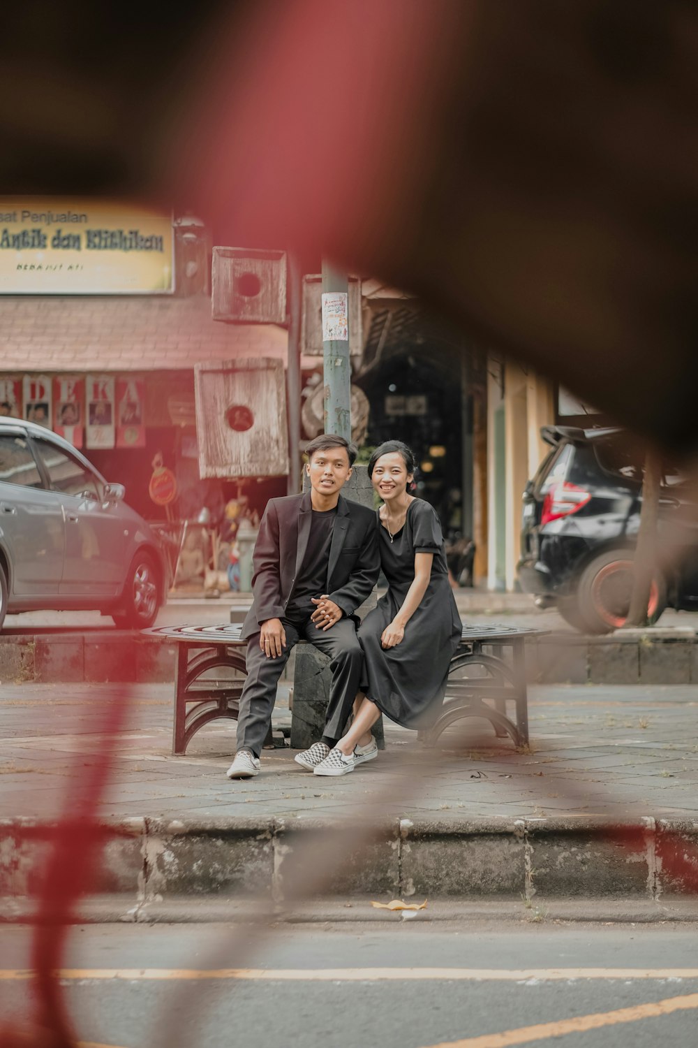 man in black thobe sitting on sidewalk during night time