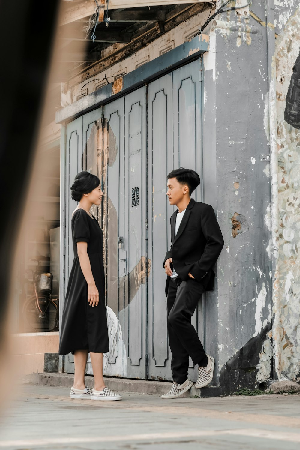 man in black coat standing beside white wooden door