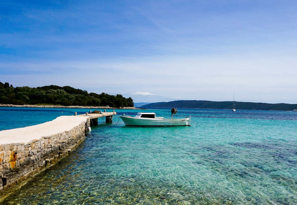 white and blue boat on sea under blue sky during daytime