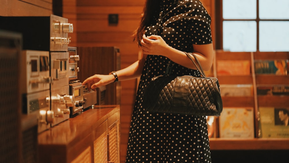 woman in black and white polka dot dress holding black leather handbag