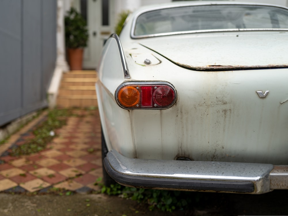 white car parked near white wooden house during daytime