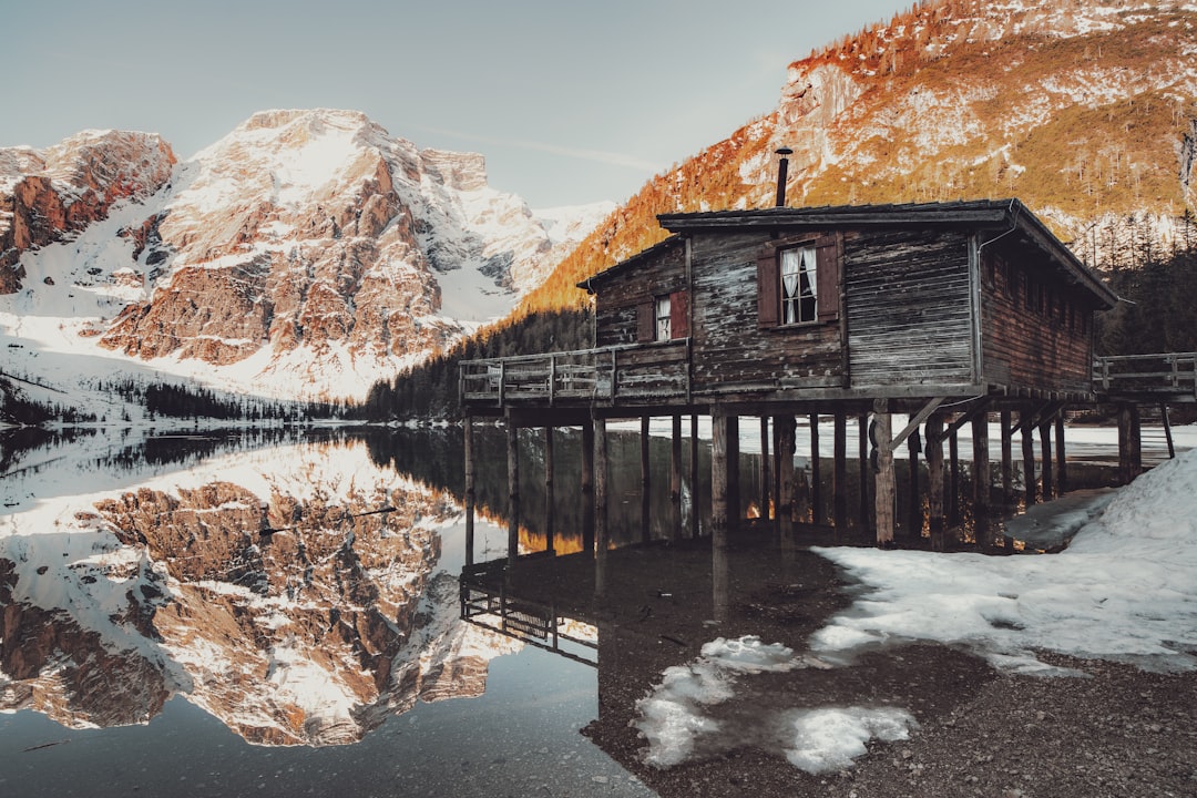 brown wooden house on lake near brown mountain during daytime