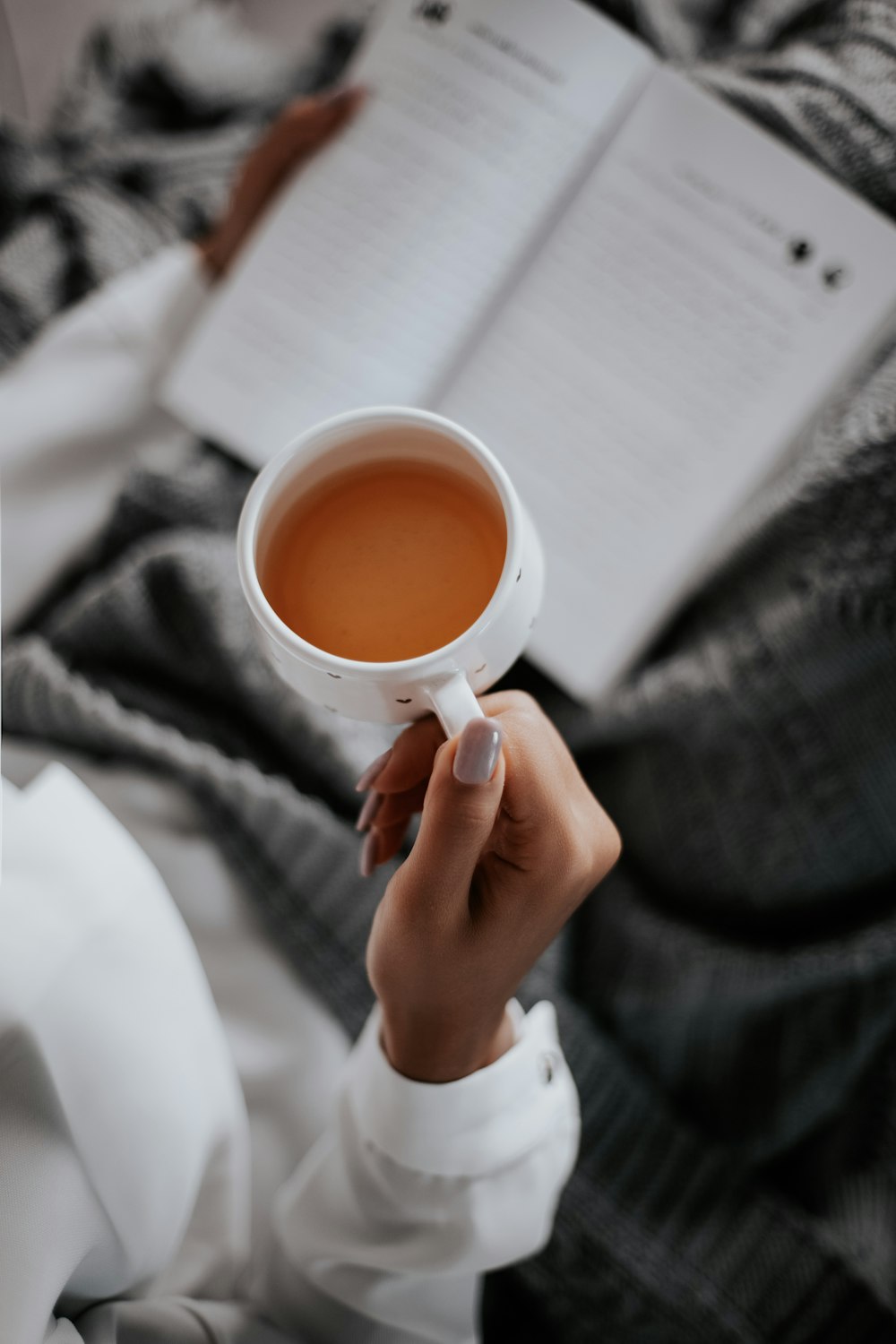 persona sosteniendo una taza de cerámica blanca