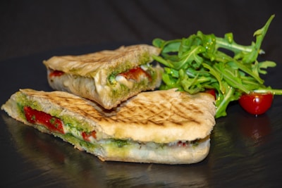 panini à base de pesto, fromage et jambon avec des la salade à coté 