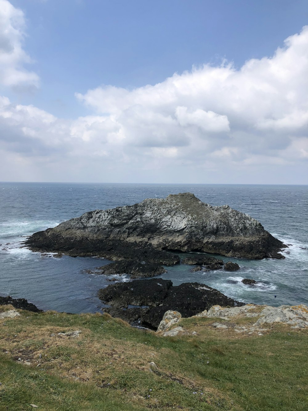 rocky shore under white clouds and blue sky during daytime