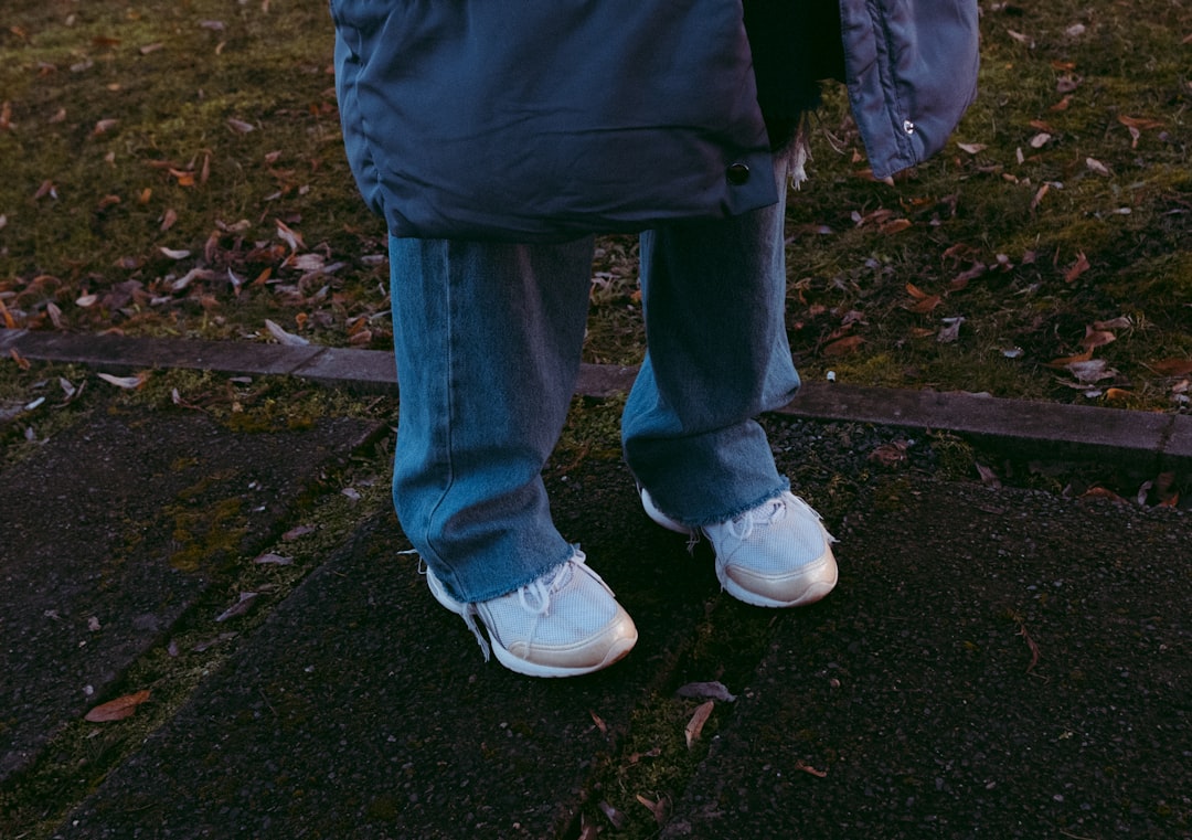 person in blue denim jeans and white sneakers