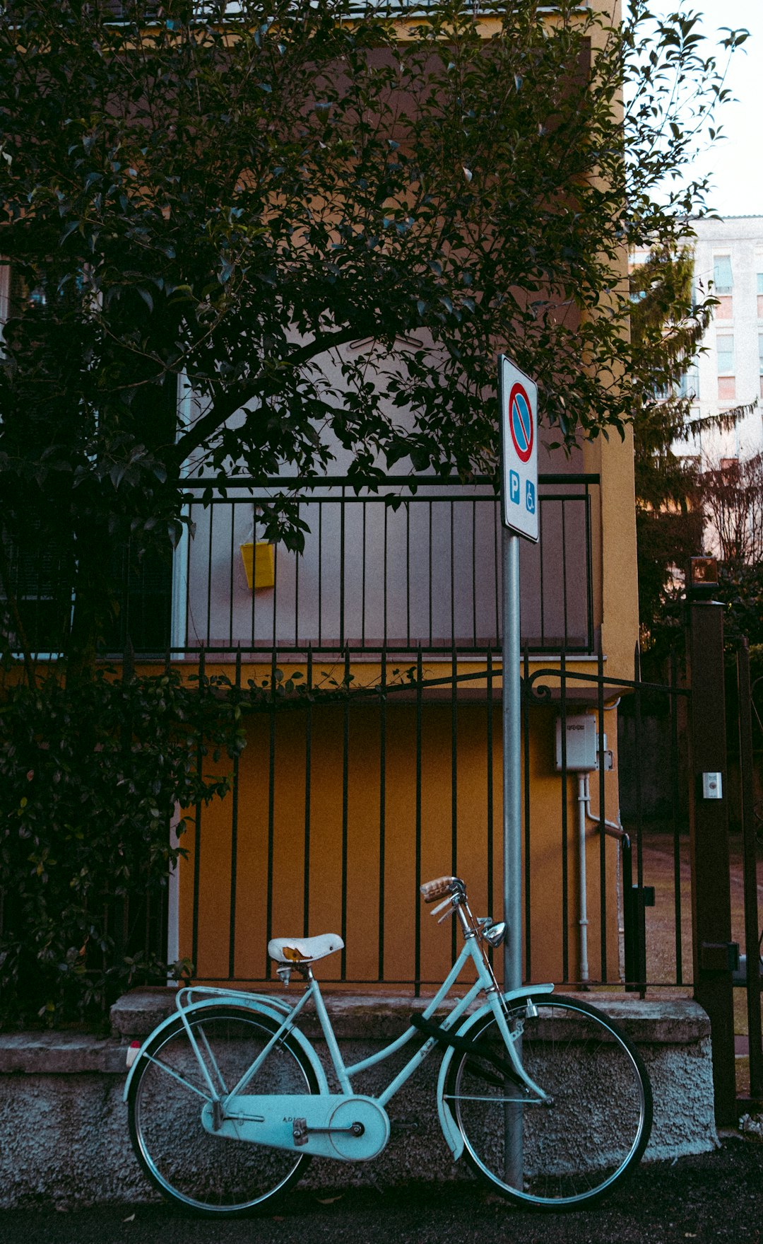 white bicycle parked beside black metal fence