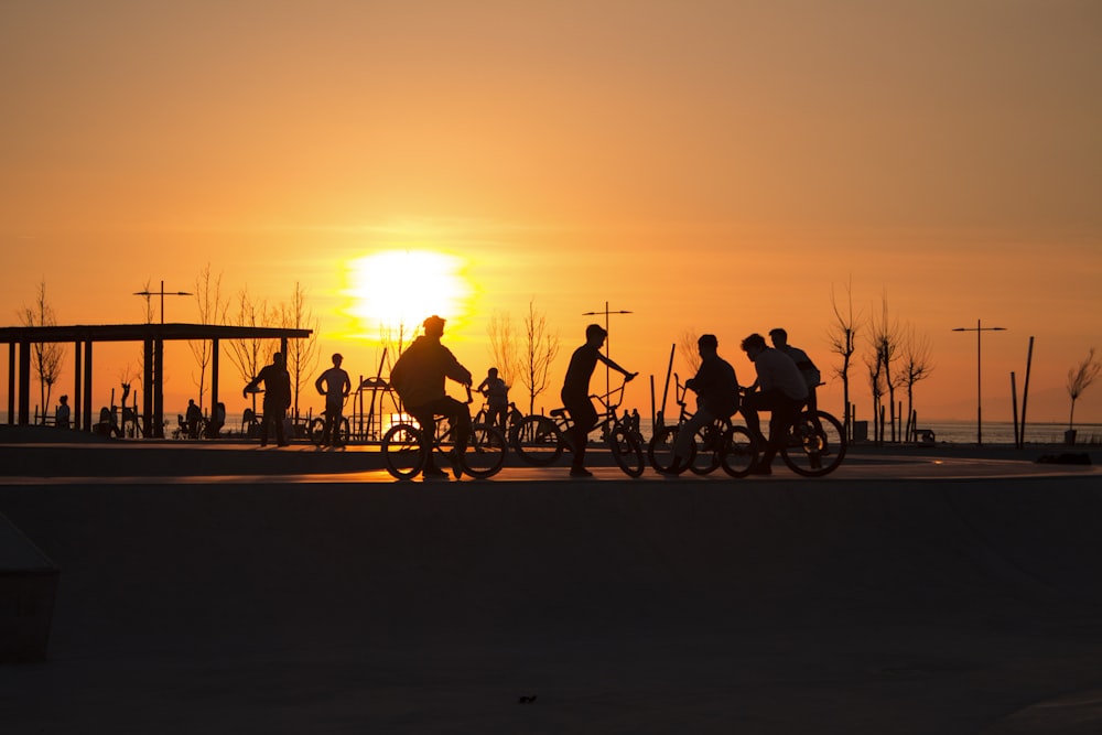 silhouette of people riding bicycles during sunset