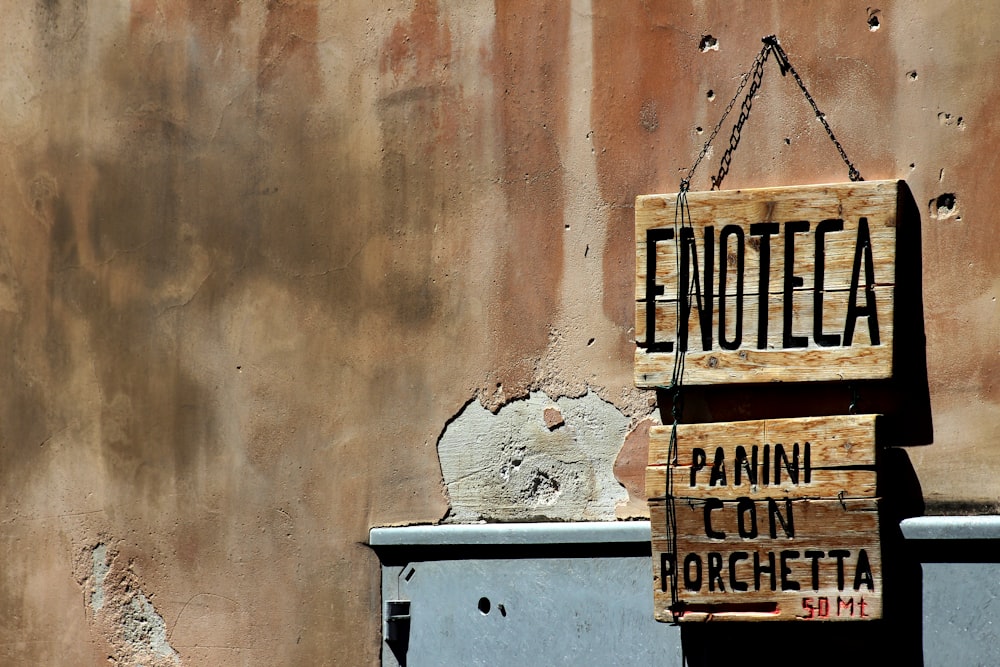 brown wooden signage on white concrete wall