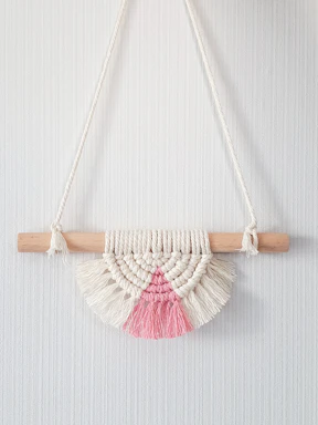 Close-up of a handwoven beige macrame wall hanging glowing in soft natural light