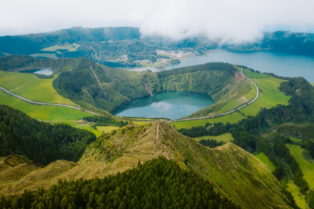 green mountain near lake under white clouds during daytime