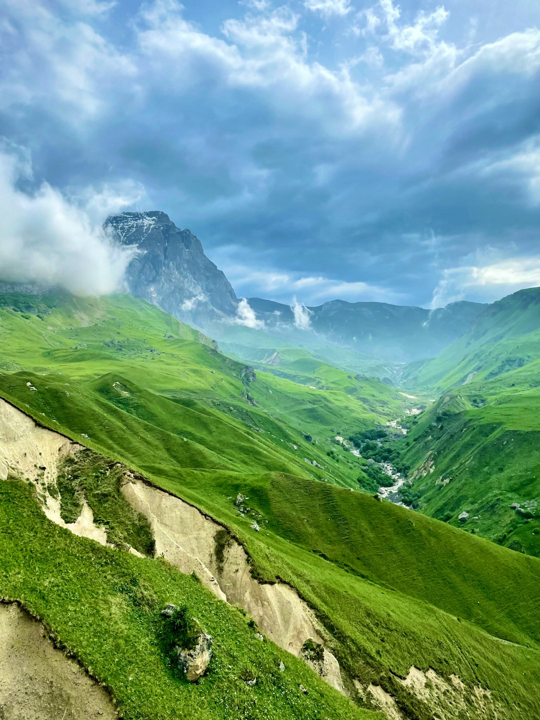 green grass covered mountain under cloudy sky during daytime