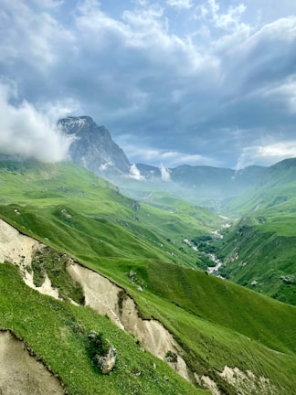 green grass covered mountain under cloudy sky during daytime