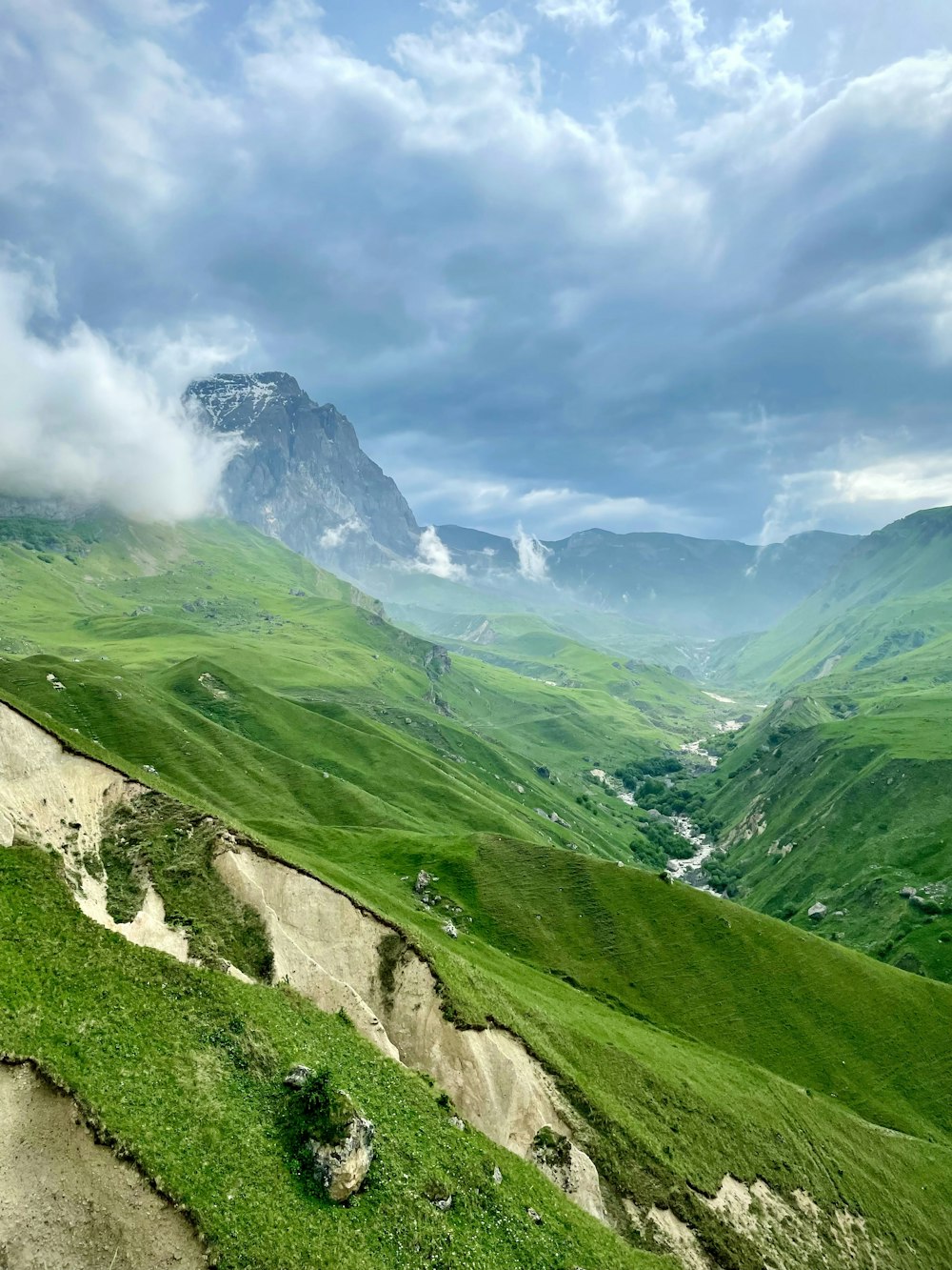 montaña cubierta de hierba verde bajo cielo nublado durante el día