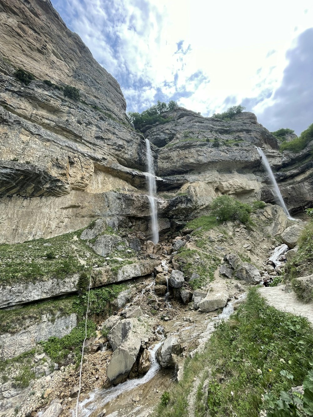 hierba verde en la montaña rocosa bajo el cielo nublado blanco durante el día