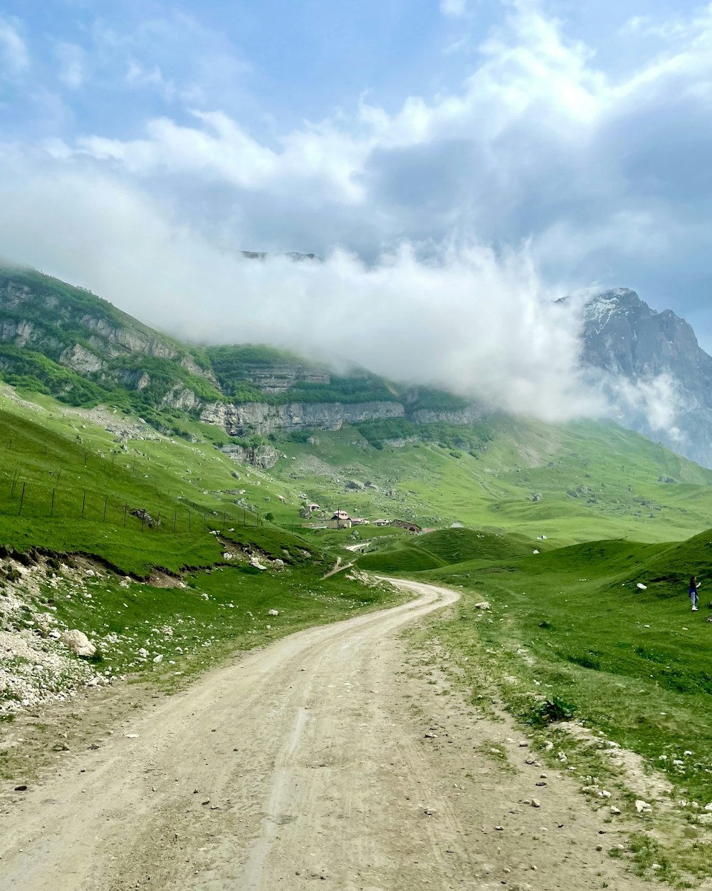 green grass field and mountain under white clouds and blue sky during daytime