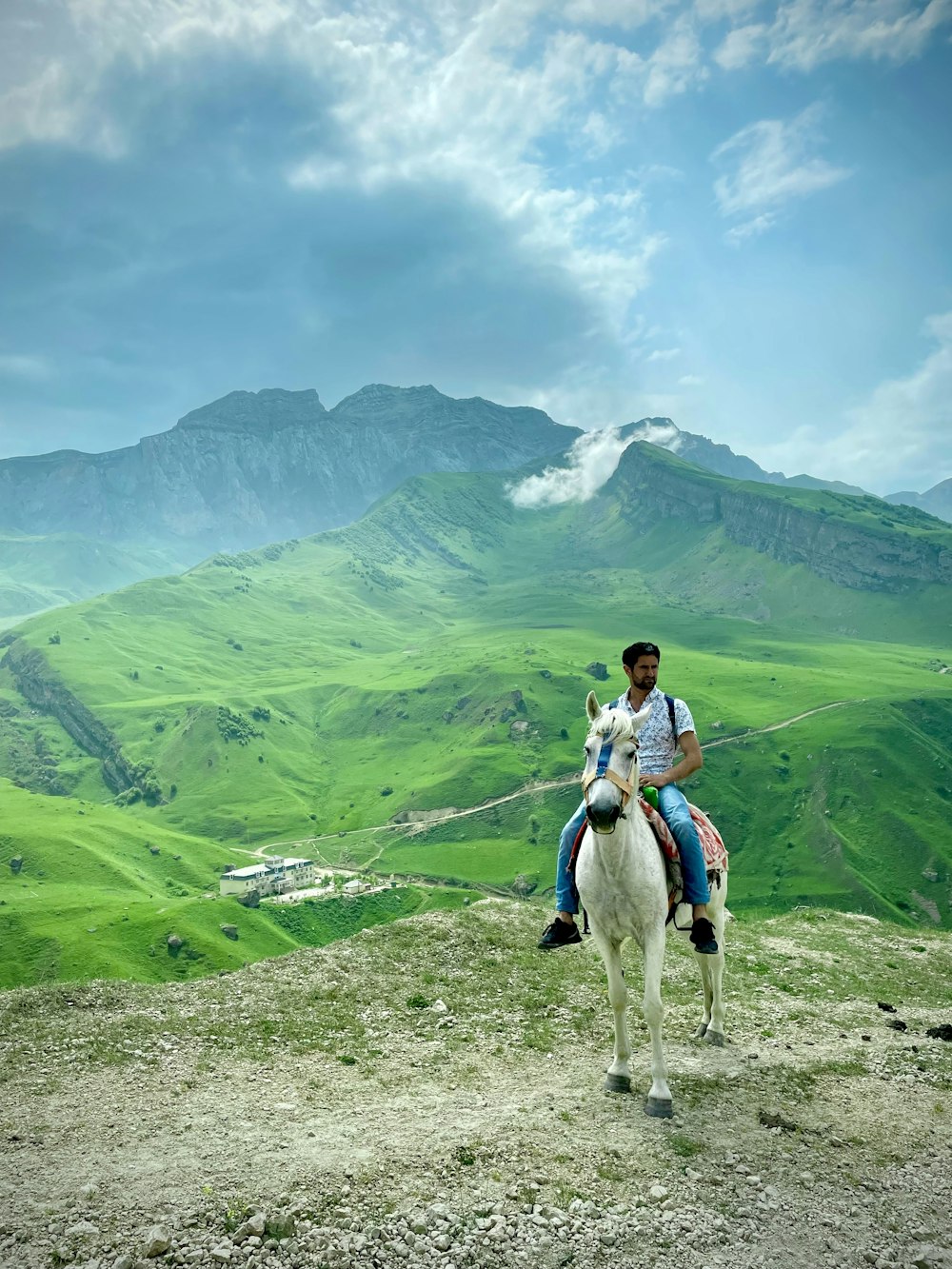 Mujer en camisa blanca de manga larga montando caballo blanco en campo de hierba verde durante el día