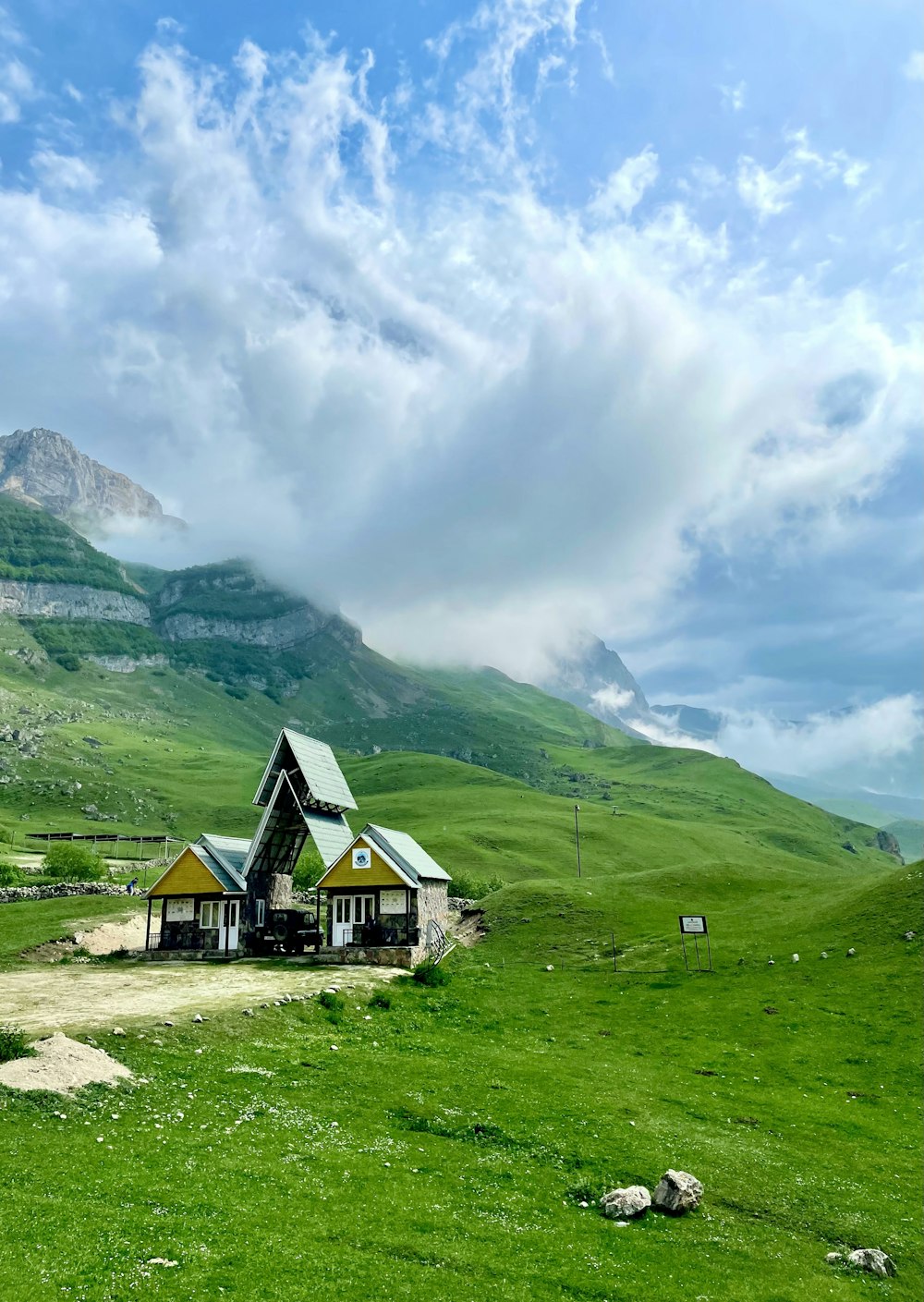 Casa verde y marrón cerca de montañas verdes bajo nubes blancas durante el día