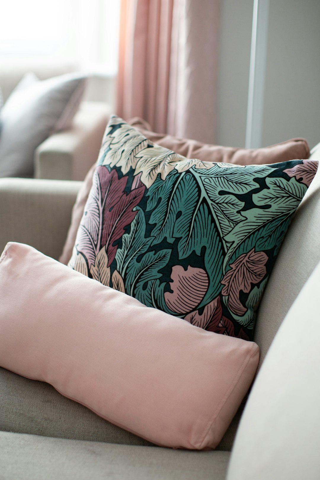  white and green floral throw pillow on pink couch cushion